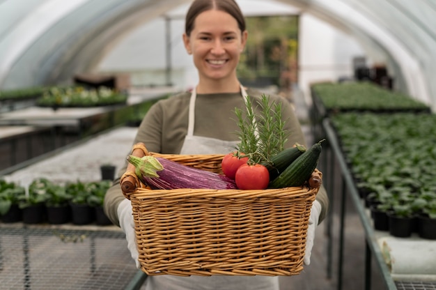 Femme souriante de coup moyen tenant un panier