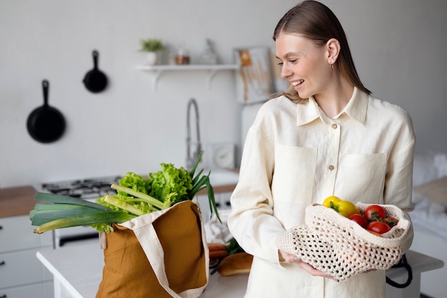 Femme souriante à coup moyen tenant un sac fourre-tout