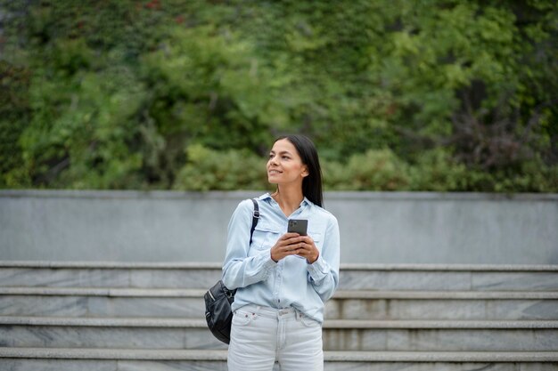 Femme souriante de coup moyen tenant un téléphone