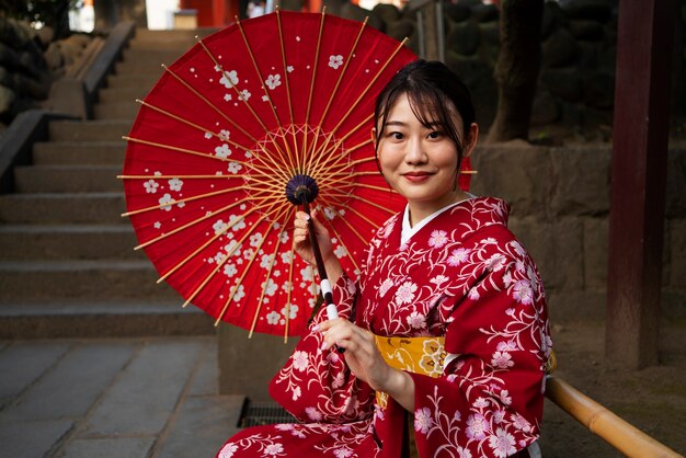 Femme souriante à coup moyen utilisant un parapluie wagasa