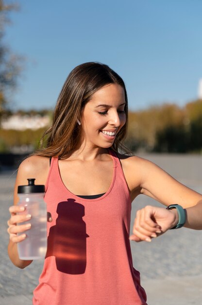 Femme souriante de coup moyen vérifiant la montre