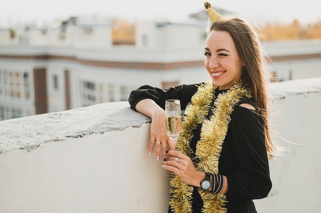 Photo gratuite femme souriante avec une coupe de champagne sur un toit