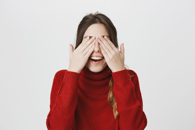 Femme souriante couvrir les yeux, attendre surprise