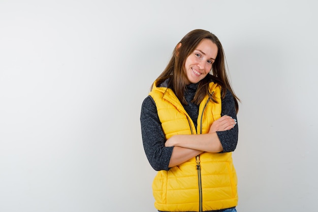 La femme souriante croise les bras sur fond blanc