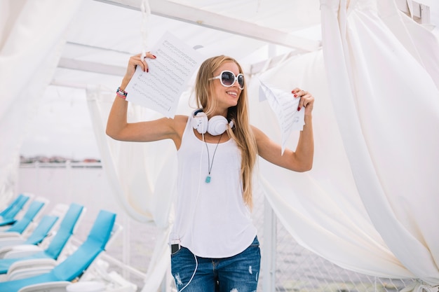 Femme souriante dans des lunettes de soleil avec de la musique