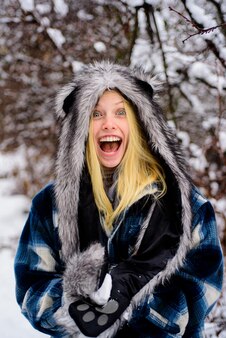 Femme souriante dans des vêtements chauds avec boule de neige belle jeune femme en hiver saison d'hiver