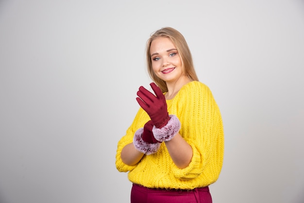 Femme souriante debout et posant dans des gants rouges.