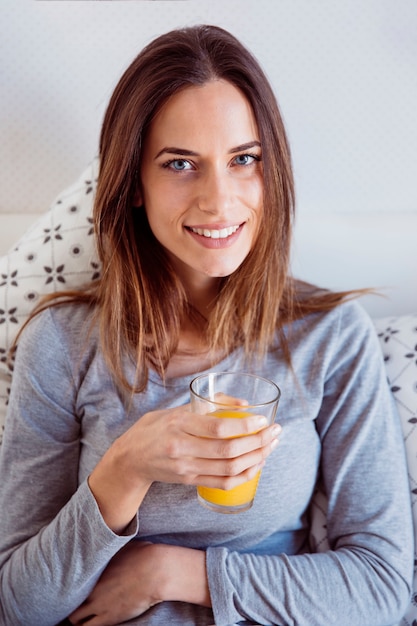 Femme souriante avec du jus au lit