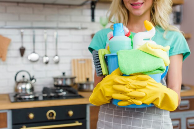 Femme souriante avec du matériel de nettoyage prêt à faire le ménage