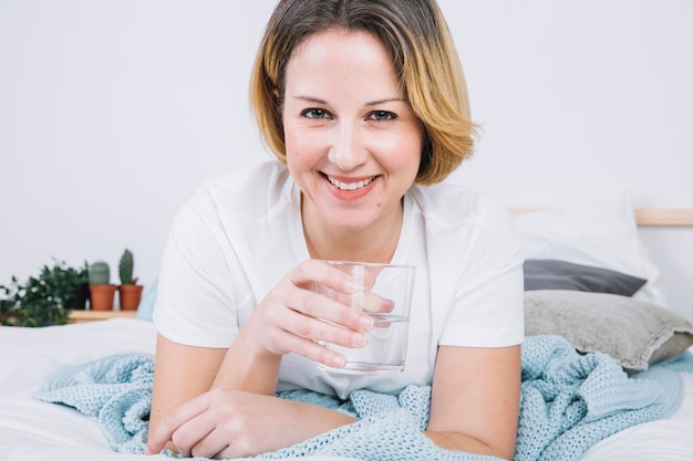 Photo gratuite femme souriante avec de l'eau sur le lit