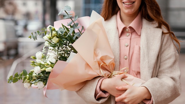 Femme souriante élégante tenant le bouquet de fleurs à l'extérieur
