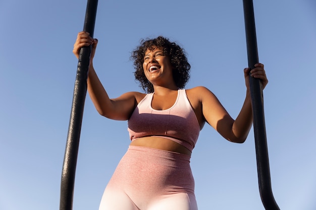 Photo gratuite femme souriante à faible angle s'entraînant à l'extérieur