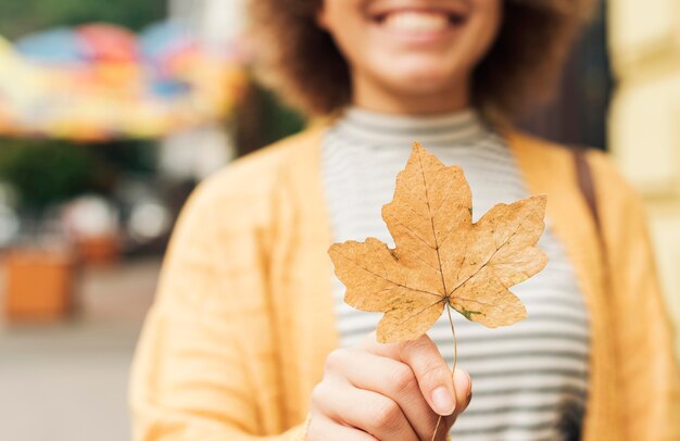 Femme souriante floue tenant une feuille sèche