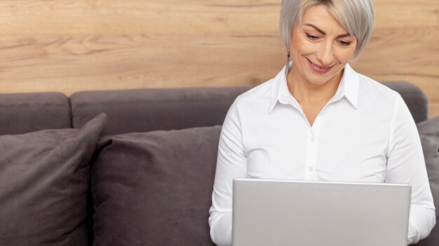 Femme souriante haute angle travaillant sur un ordinateur portable