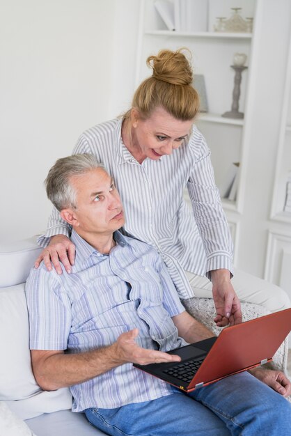 Femme souriante avec homme surpris et ordinateur portable