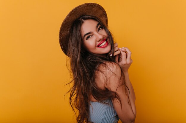 Femme souriante intéressée avec une coiffure longue regardant par-dessus l'épaule