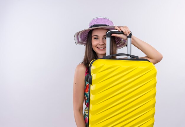 Femme souriante jeune voyageur tenant valise sur mur blanc isolé