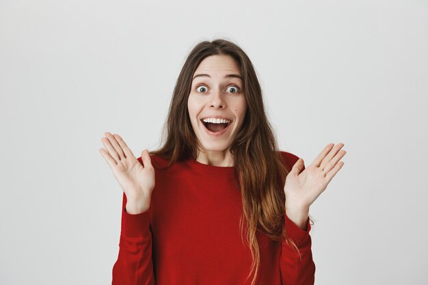 Femme souriante joyeuse et excitée se sentant heureuse, joignent les mains sur de bonnes nouvelles