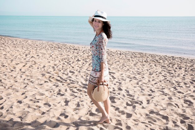 Femme souriante marchant sur la plage