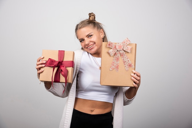 Femme souriante montrant des cadeaux de vacances avec une expression heureuse.