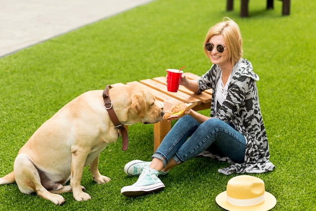 Femme souriante montrant de la nourriture à son chien