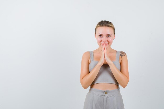 La femme souriante montre un geste de remerciement avec les mains sur fond blanc