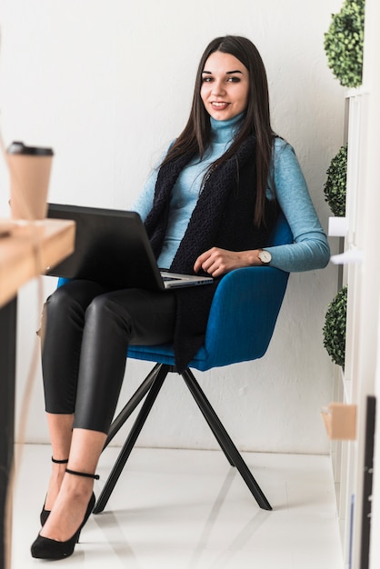 Femme souriante avec ordinateur portable au bureau