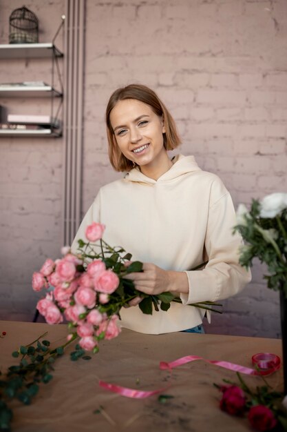 Femme souriante de plan moyen avec un bouquet de fleurs