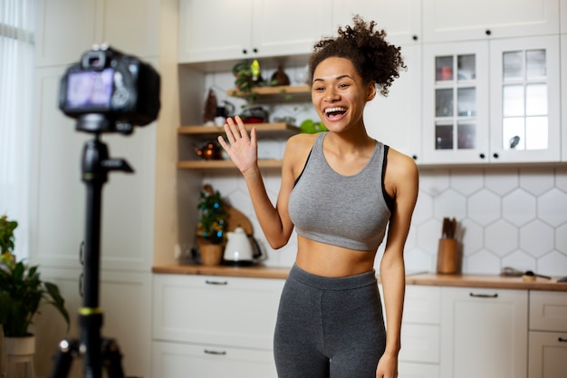 Femme souriante de plan moyen avec caméra vidéo