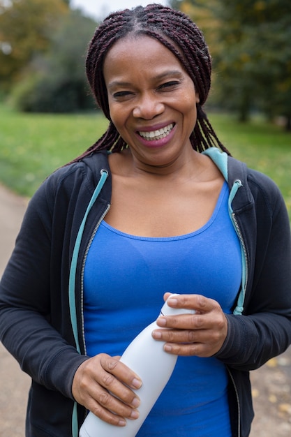 Femme souriante de plan moyen avec de l'eau