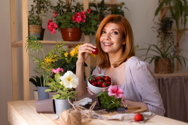 Femme souriante de plan moyen avec des fraises