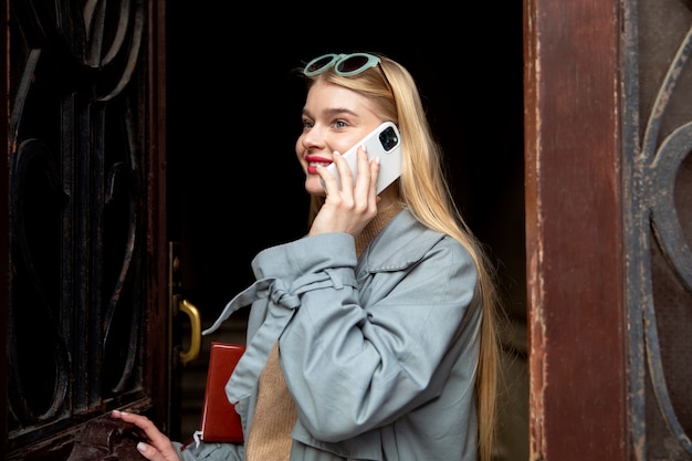 Femme souriante de plan moyen parlant au téléphone