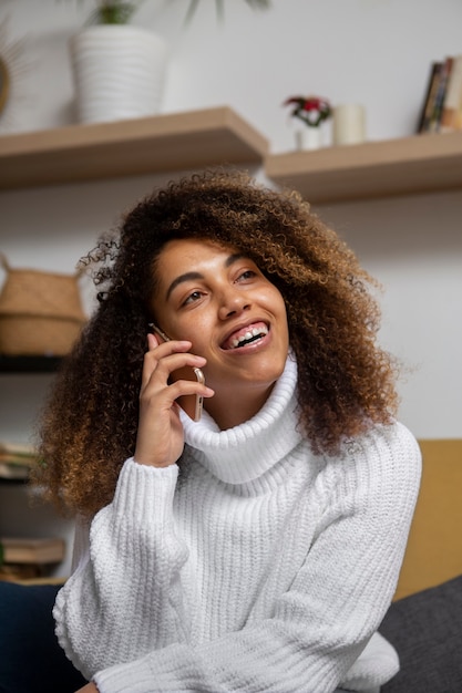 Femme souriante de plan moyen parlant au téléphone