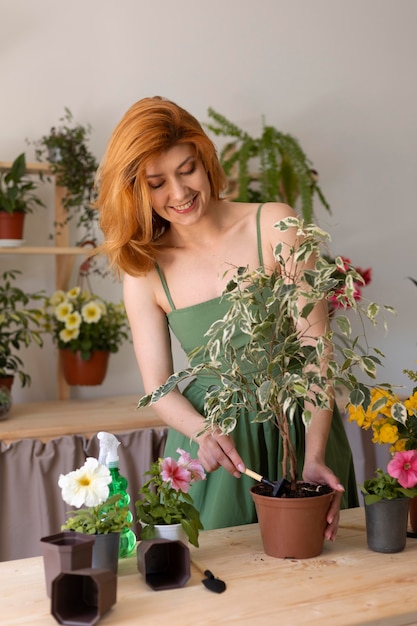 Femme souriante de plan moyen avec une plante