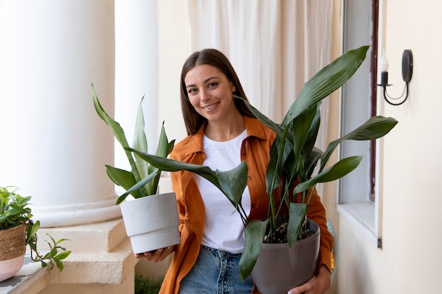 Femme souriante de plan moyen portant des plantes