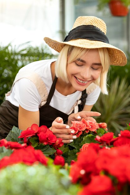 Femme souriante de plan moyen regardant des fleurs
