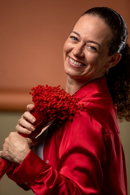 Femme souriante de plan moyen tenant des fleurs