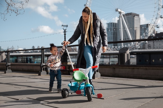 Photo gratuite femme souriante plein coup marchant avec un enfant à l'extérieur