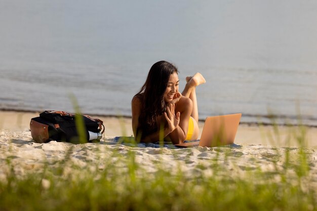 Femme souriante de plein coup travaillant à la plage