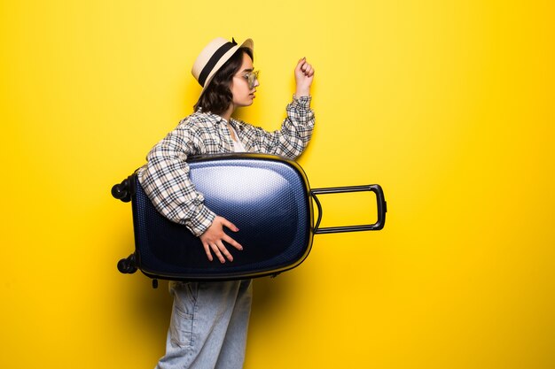 Femme souriante portant des lunettes de soleil et un chapeau avec valise courir isolé