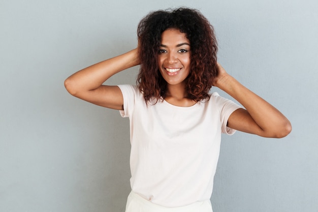 Femme souriante posant et jouant avec ses cheveux en position debout