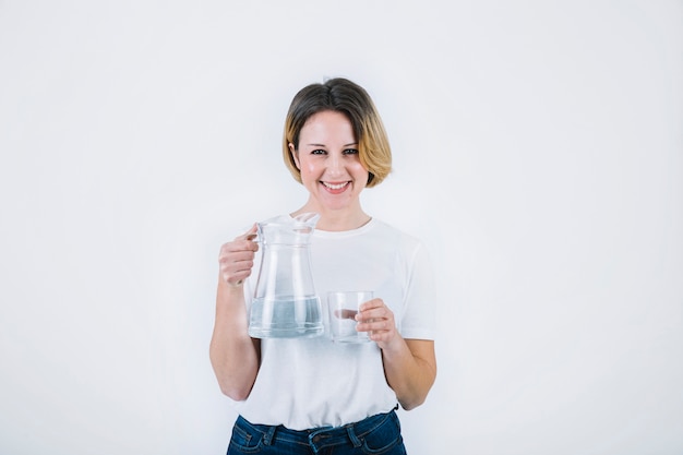 Femme souriante posant avec pichet et verre