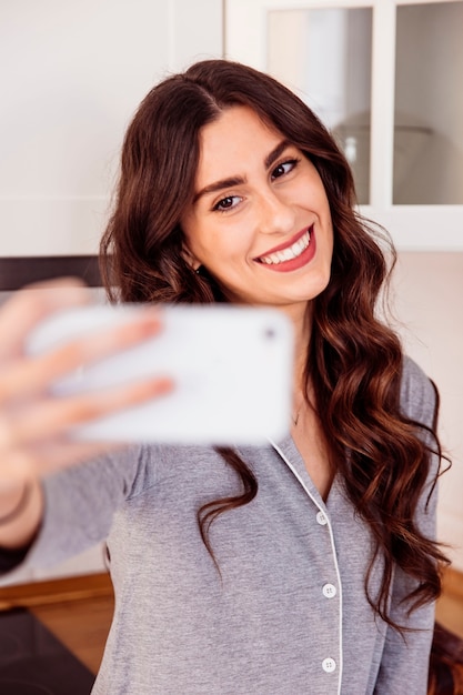 Femme souriante prenant selfie dans la cuisine