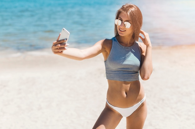 Femme souriante prenant selfie près de la mer