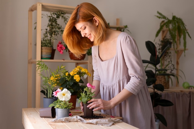 Femme souriante prenant soin d'un coup moyen de fleur