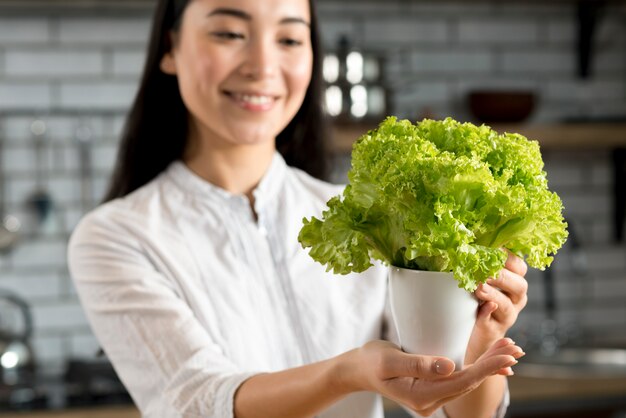 Femme souriante, projection, vert, laitue fraîche, dans, pot