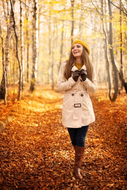 Femme souriante qui marche dans le parc à la saison d'automne