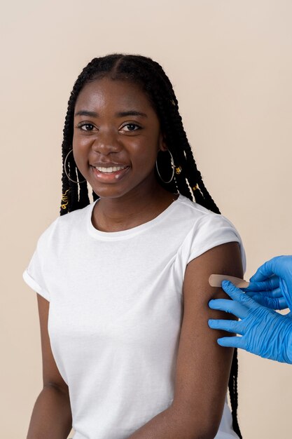 Femme souriante recevant un autocollant sur le bras après avoir reçu un vaccin
