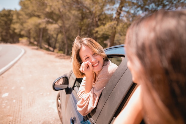 Femme souriante regardant un ami en voiture