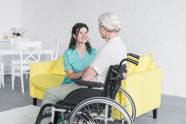 Femme souriante regardant une femme senior assis sur une chaise roulante